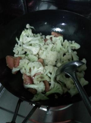 锅内放入适量油，把菜花放入锅内翻炒到九成熟，然后放入西红柿