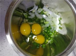 切碎的青椒和葱花放入大的容器内鸡蛋放进去，拌匀