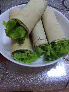 把准备好的生菜放入甜面酱（根据个人喜好添加）
把胡萝卜和生菜放入准备好的长方形豆腐皮中，慢慢卷起即可。如图5.6