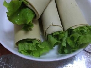 把准备好的生菜放入甜面酱（根据个人喜好添加）
把胡萝卜和生菜放入准备好的长方形豆腐皮中，慢慢卷起即可。如图5.6