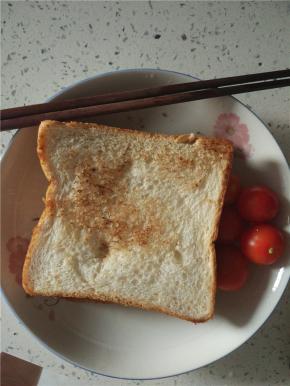 再放上另外一片面包，用牙签固定，切小块，配小番茄