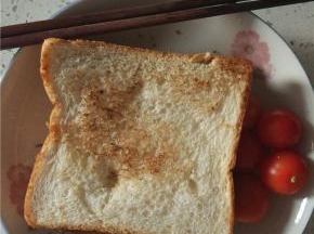 再放上另外一片面包，用牙签固定，切小块，配小番茄