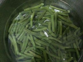 把芸豆摘好，清洗干净，把芸豆切成段状。水烧开之后，把切好的芸豆放入水中，煮3分钟左右，捞出。
