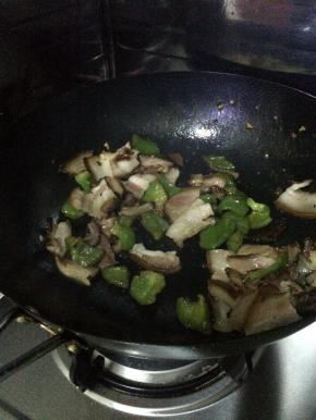把腊肉放入锅中翻炒一分钟左右，加入青椒翻炒，