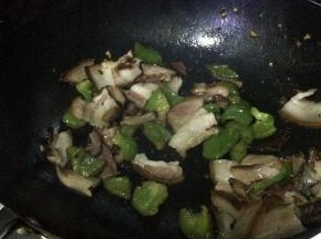 把腊肉放入锅中翻炒一分钟左右，加入青椒翻炒，