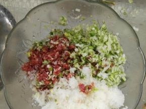 把准备好的白萝卜、葱、姜、肉都剁成碎状。放入盆中。