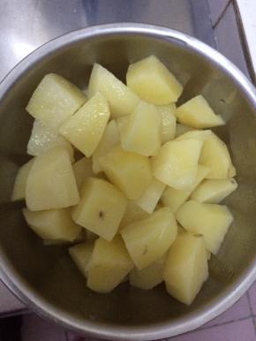 把煮熟的土豆从锅内捞出，切成块状。