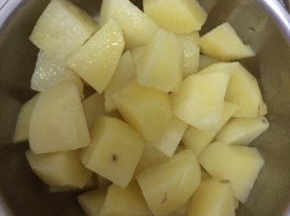 把煮熟的土豆从锅内捞出，切成块状。