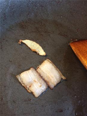 起锅放一点油，下入五花肉片和姜片小火煸至肉片透明，边缘略焦。