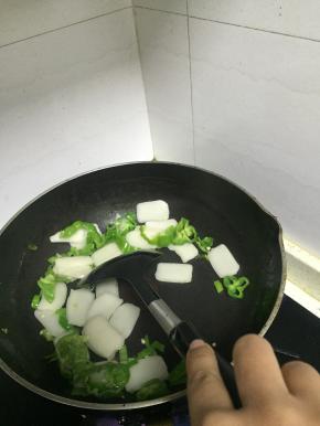 待青椒变软后，加入年糕片，翻炒1-2分钟