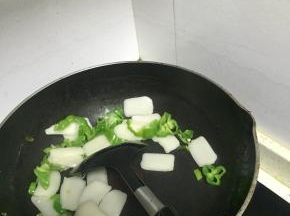 待青椒变软后，加入年糕片，翻炒1-2分钟