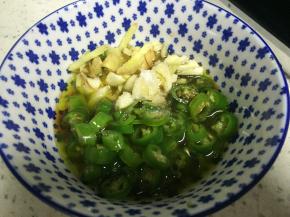 将滚烫的热油倒入尖椒、姜末和蒜中