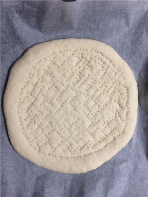 二次发酵好的面饼取出，留出饼边，中间用叉子均匀地扎上小孔，刷上一层番茄酱
