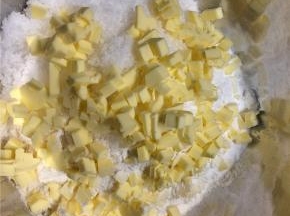 黄油回室温切成小粒，放到面粉中一起搓成屑状