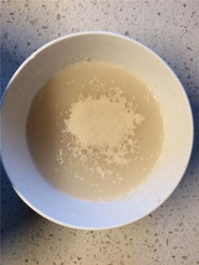 在温水中加入少许白糖，搅拌至白糖融化后加入酵母，静置10分钟
