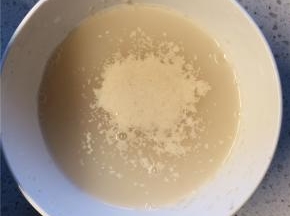 在温水中加入少许白糖，搅拌至白糖融化后加入酵母，静置10分钟