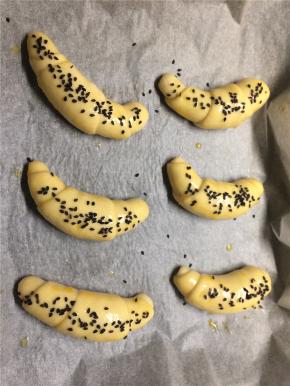 再次发酵好的面包取出表面刷上鸡蛋液，撒上黑芝麻。