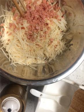 火腿切小丁加入土豆丝，适量盐、胡椒粉调味拌匀