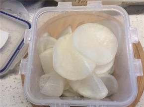 将腌出的水倒掉后，用凉水清洗萝卜片，挤去水分，放在要腌的容器里