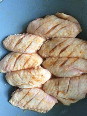 烤翅腌料加少量水润湿，均匀地涂抹在鸡翅两面，封上保鲜膜放冰箱冷藏过夜