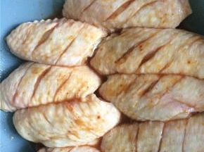 烤翅腌料加少量水润湿，均匀地涂抹在鸡翅两面，封上保鲜膜放冰箱冷藏过夜