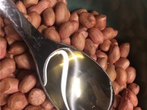 花生米放在大碗里，倒一勺食用油拌匀，使每颗花生米表面都裹上一层薄油