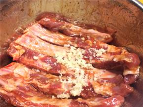 几瓣大蒜压成蒜蓉，和其他调料一起混匀，均匀地抹在每一根肋排上，用保鲜膜密封入冰箱冷藏腌制过夜