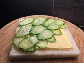 取一片吐司，放上芝士片，再均匀地铺上黄瓜薄片