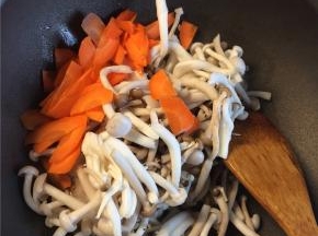 起锅热油下入蒜片煸至金黄后，下入蘑菇和胡萝卜