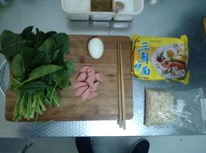 准备好要用到的各种食材，从左到右依次为菠菜、香肠、水煮蛋、三鲜面。香肠切段，泡面拆开。