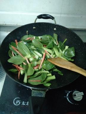 小葱出香味后迅速将青菜和胡萝卜倒进锅里，快速翻炒，不要让小葱炒糊
