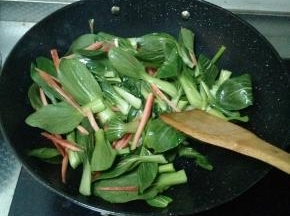 小葱出香味后迅速将青菜和胡萝卜倒进锅里，快速翻炒，不要让小葱炒糊