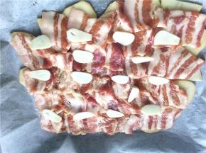 再平铺上一层腌好的五花肉片，均匀地撒上蒜片姜丝。