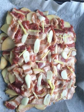 按照土豆片+五花肉+姜丝蒜片的顺序将所有食材都铺在烤盘内