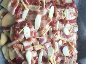 按照土豆片+五花肉+姜丝蒜片的顺序将所有食材都铺在烤盘内