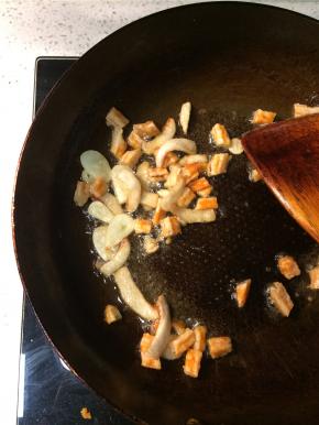 转大火下入蒜片和切段的虾干爆炒一分钟