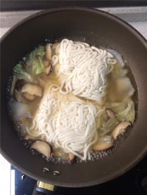 转大火下入乌冬面，煮3分钟左右至面条熟透