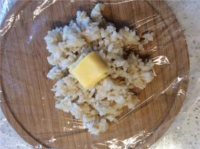 舀适量米饭放在保鲜膜上，在米饭的中间放上芝士块