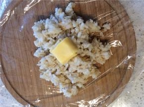 舀适量米饭放在保鲜膜上，在米饭的中间放上芝士块