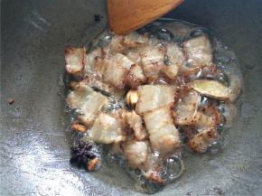 下入五花肉片，加入一勺白糖翻炒至肉片出油、边缘略焦黄