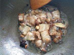 下入五花肉片，加入一勺白糖翻炒至肉片出油、边缘略焦黄