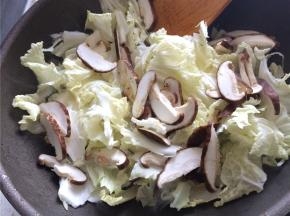 下入白菜片和香菇翻炒两分钟，加入老抽上色，翻炒均匀