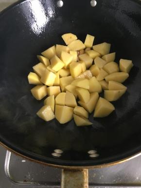 3.大蒜切片，炒锅入油后倒入大蒜片爆香，再加入土豆。