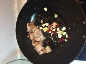 五花肉煸炒至白色后加入姜蒜和干辣椒，