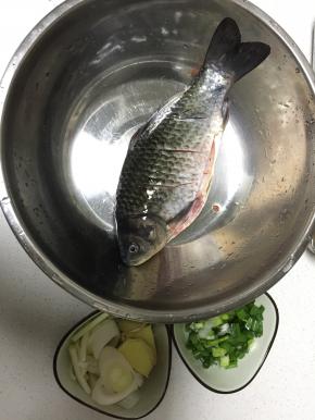 将鲫鱼洗干净，背上切几刀，用盐抹匀腌制半天，准备好姜、大葱、小葱，