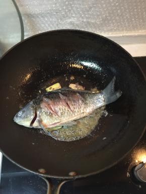 煸炒到鱼皮金黄色后，加入料酒去腥味