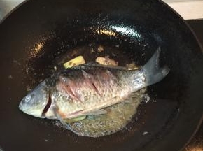 煸炒到鱼皮金黄色后，加入料酒去腥味