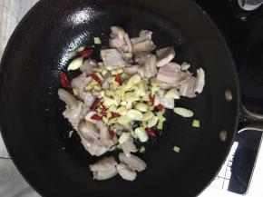 当五花肉变白时，把蒜、姜、干辣椒放进去一起炒