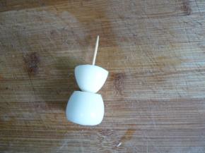 鹌鹑蛋煮熟去壳，将两端用刀削平。用牙签将两个鹌鹑蛋串成雪人状。