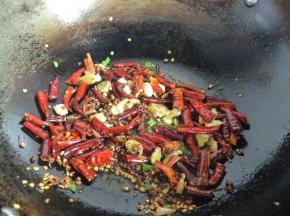 锅中留适量底油，先放入花椒炒出香味；再下蒜片、姜片爆香；然后再放入辣椒段炒出香味，最后撒入葱花。